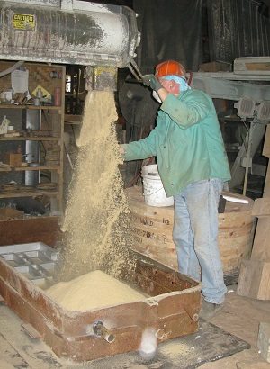 A picture of a man operating a tall sand casting machine from Quaker City Castings
