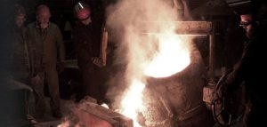Iron Casting - A picture of two men pouring liquid metal into an open hearth at the Quaker City Casting foundry.