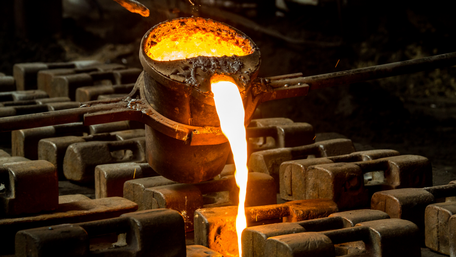 Molten metal being poured into a sand casting.